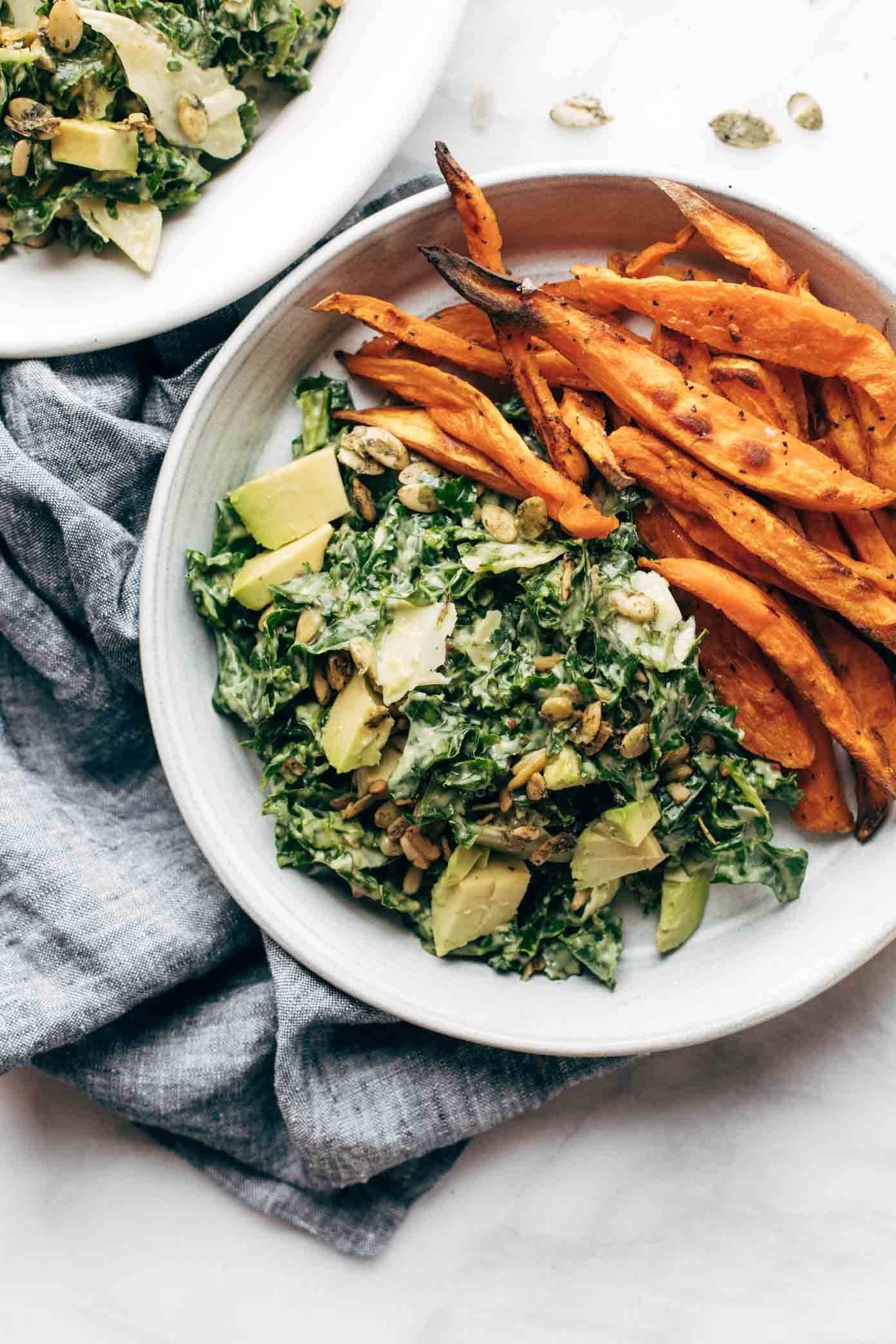 Kale caesar salad on a plate with sweet potato fries.