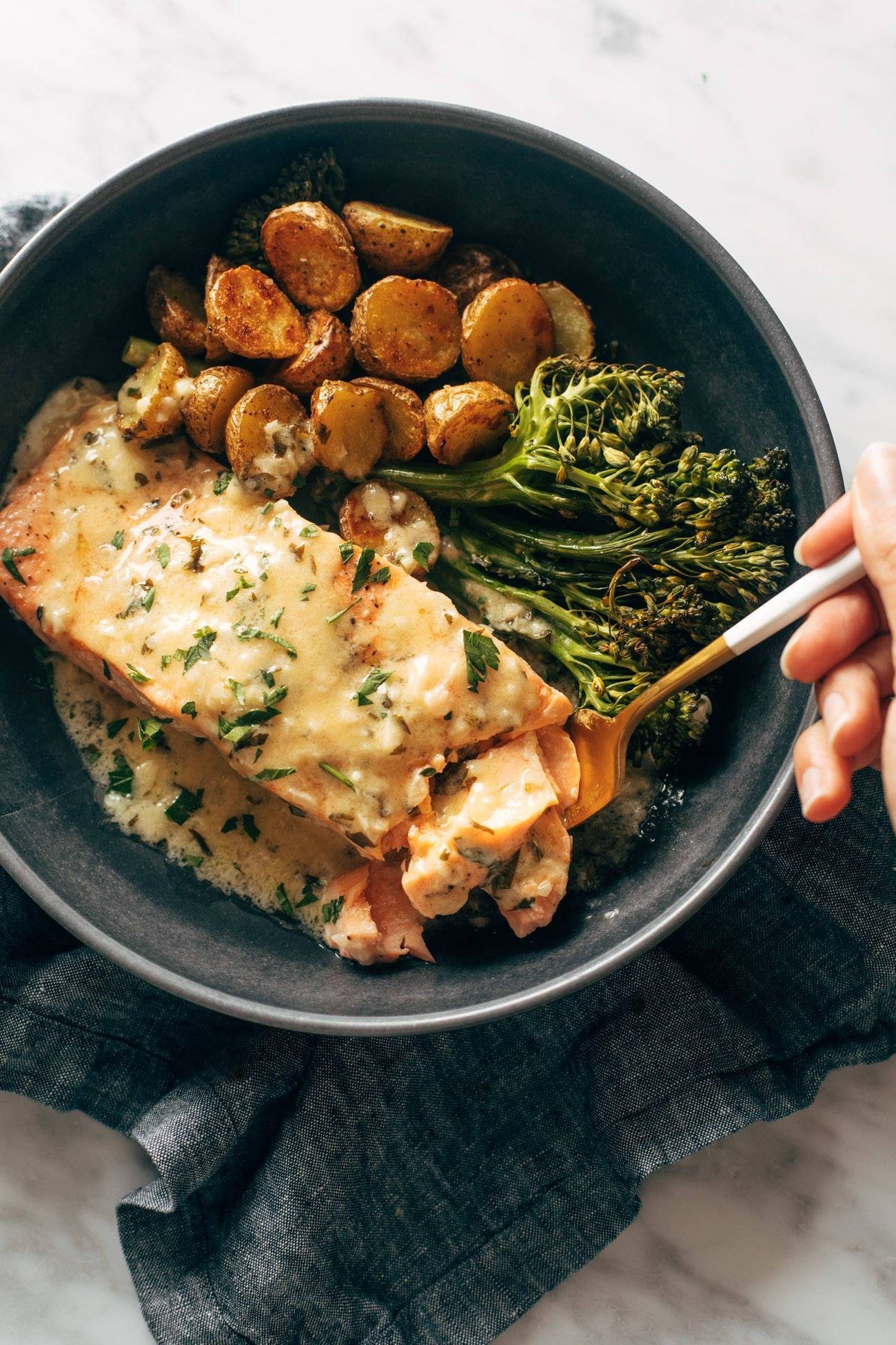 Salmon in a bowl creamy lemon sauce, potatoes, and broccoli.