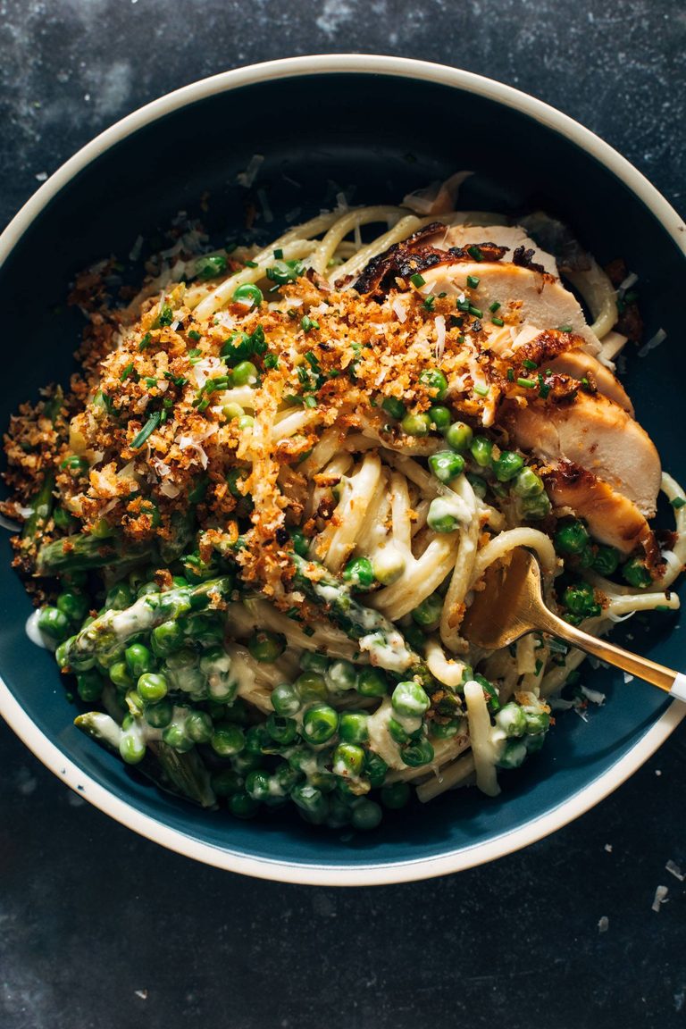 Garlic cream bucatini in a bowl with peas and chicken.