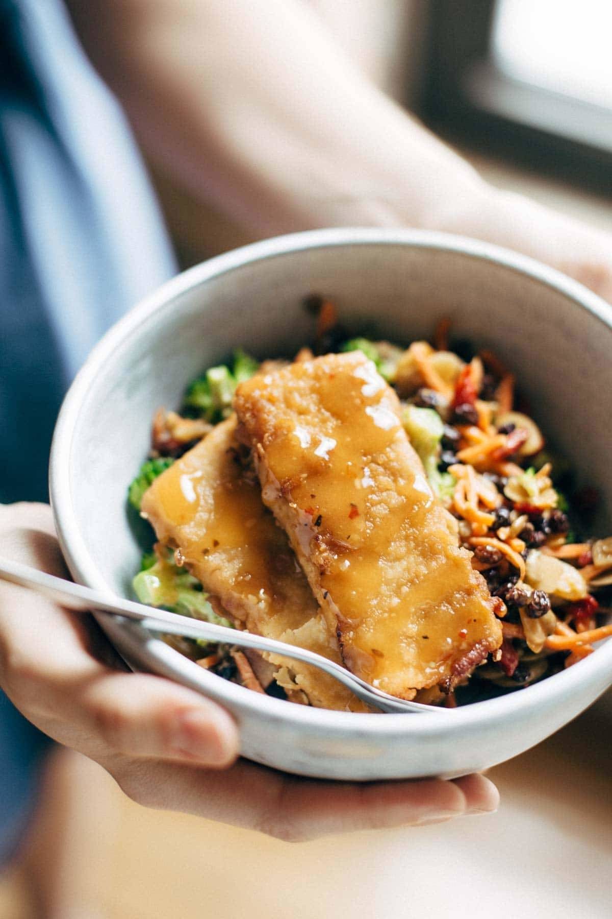 Hands holding a bowl of food.