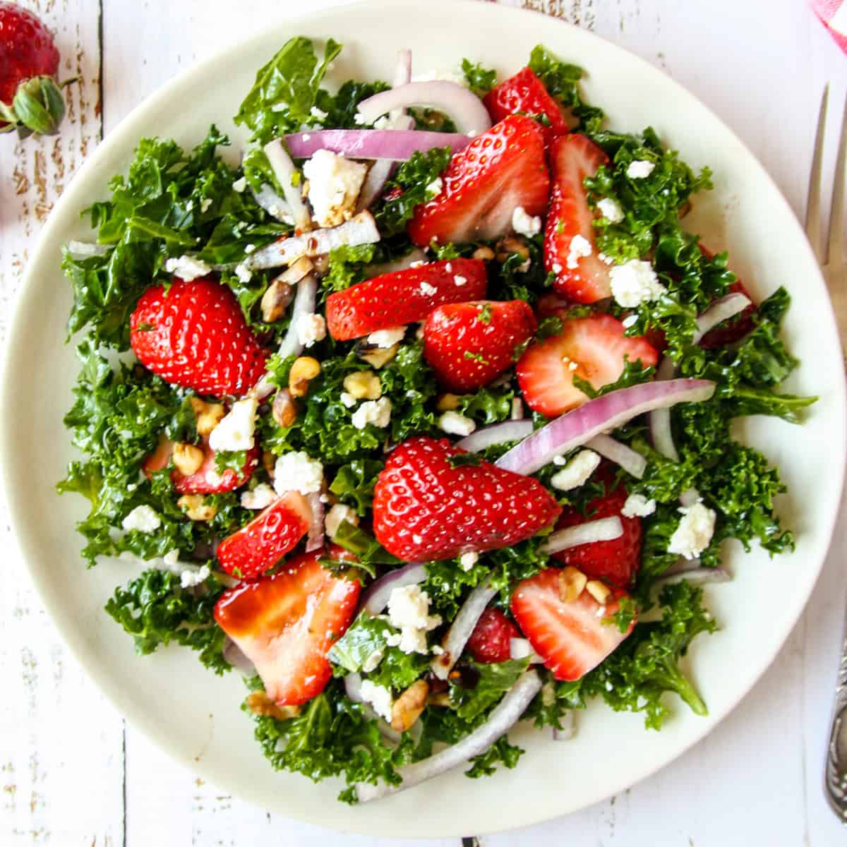 Strawberry kale salad on a white plate.