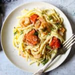 Shrimp and salmon alfredo on a white plate, with a silver fork.