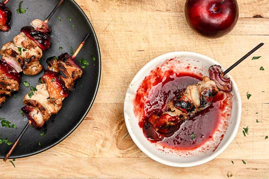 A skewer of grilled meat is dipped in sauce