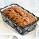 A loaf of cranberry walnut bread in a black and white ceramic pan.