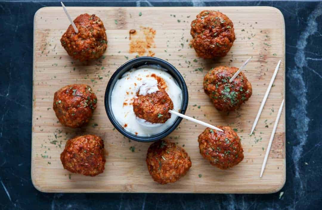 A meatball on a toothpick is being dipped in sauce