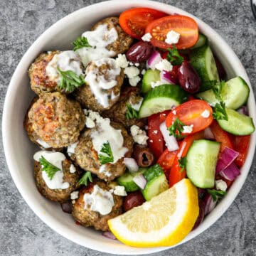 Greek chicken meatballs and Greek salad in a white bowl.