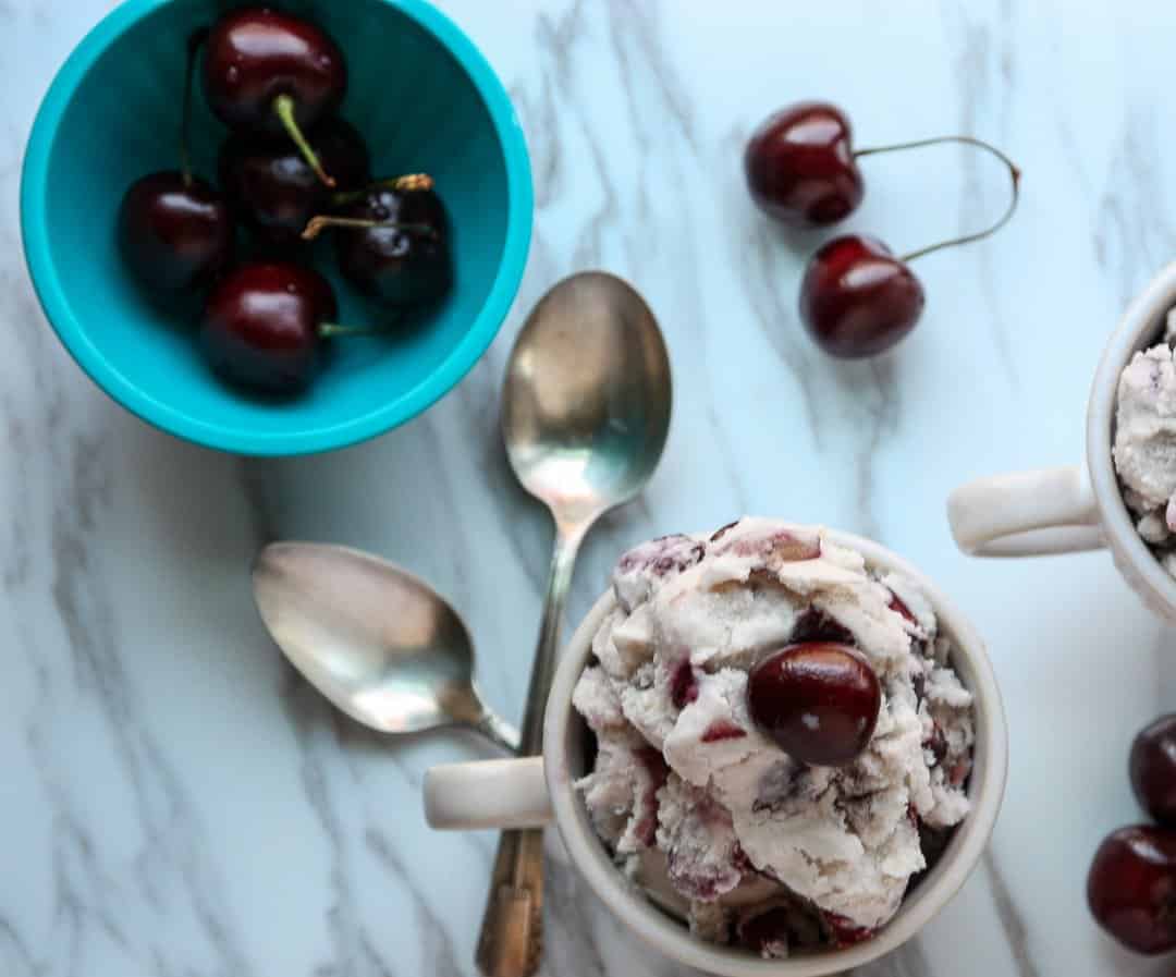 A bowl of cherries on a plate, with Ice cream