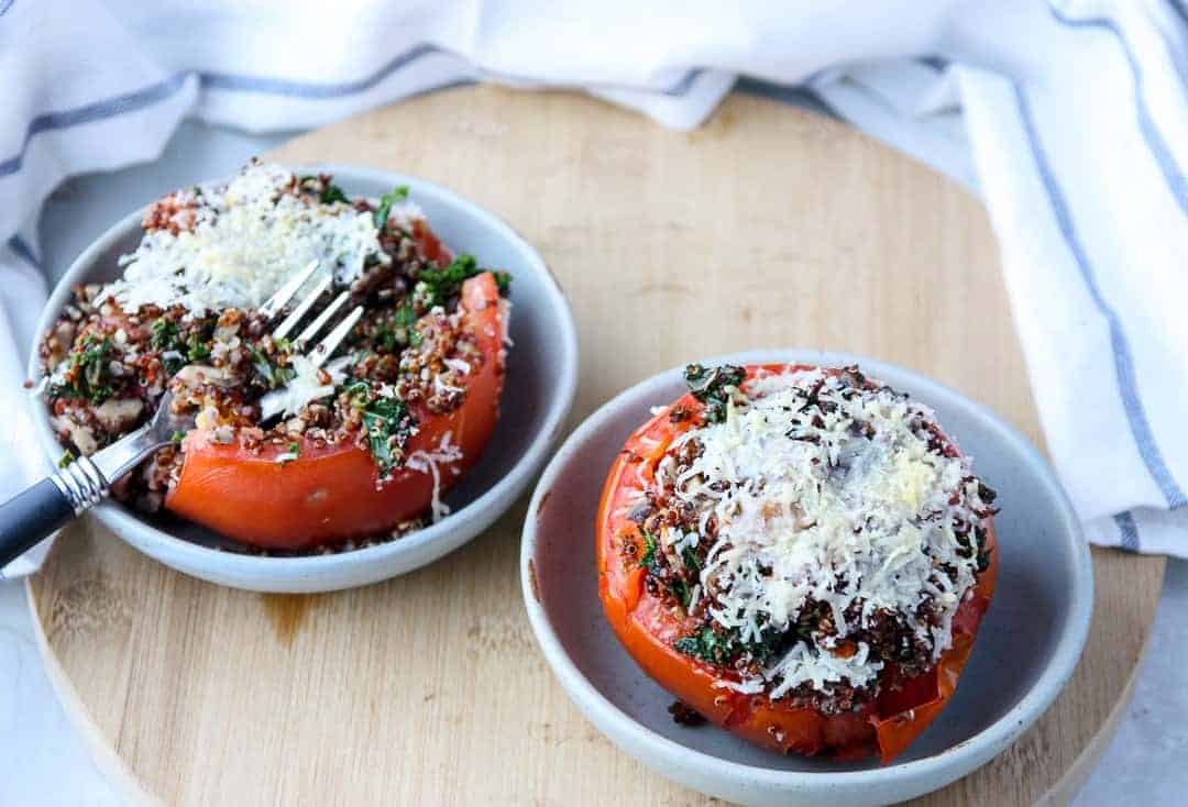 Two bowls with stuffed tomatoes topped with cheese