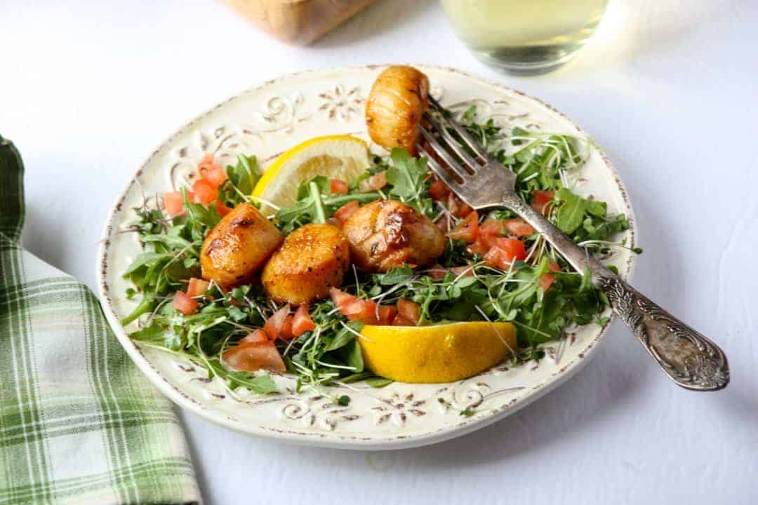 A plate of food on a table, with Scallops and Chardonnay