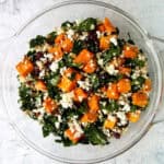Butternut squash salad with feta, buckwheat and kale, in a glass bowl.