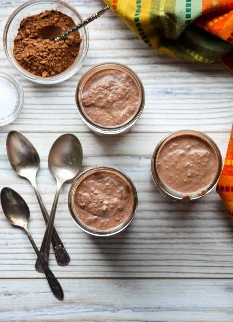 A wooden table topped with jars of pudding and spoons