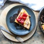 A large pancake in a pan on a table, topped with strawberries.