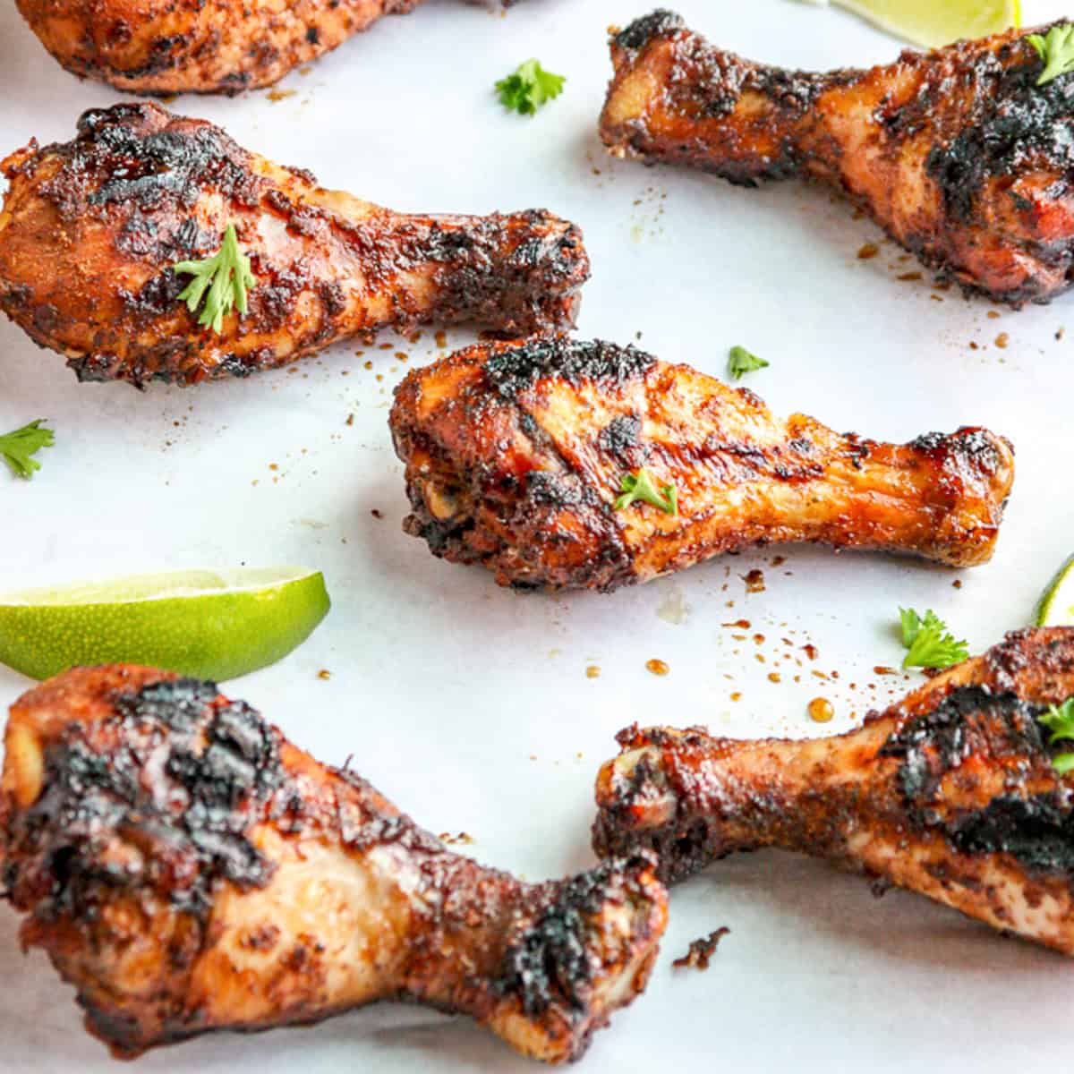 A platter full of grilled jerk chicken drumsticks.