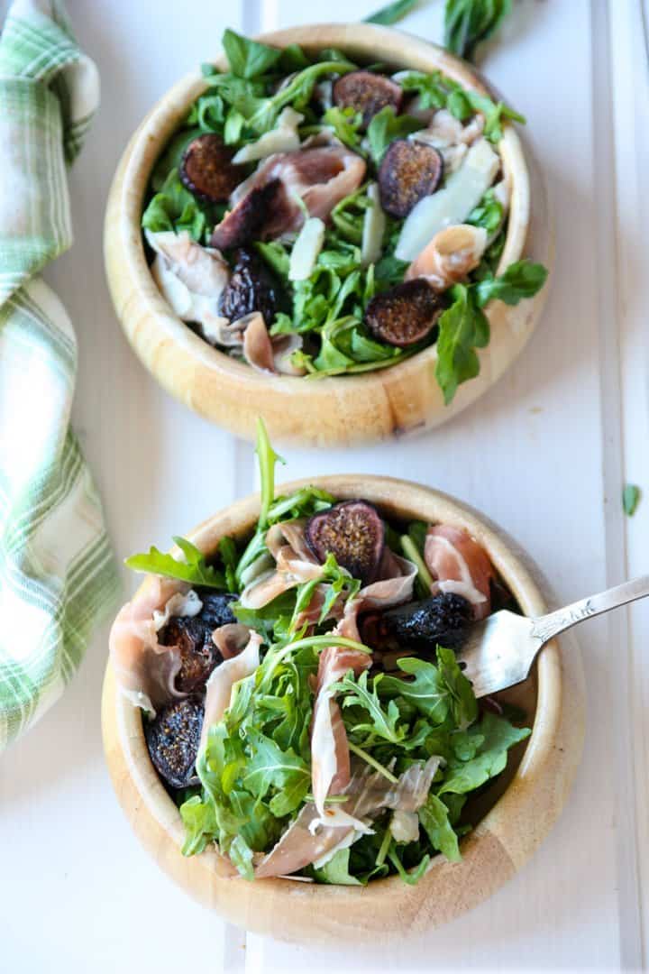 A bowl of salad on a plate, with Arugula