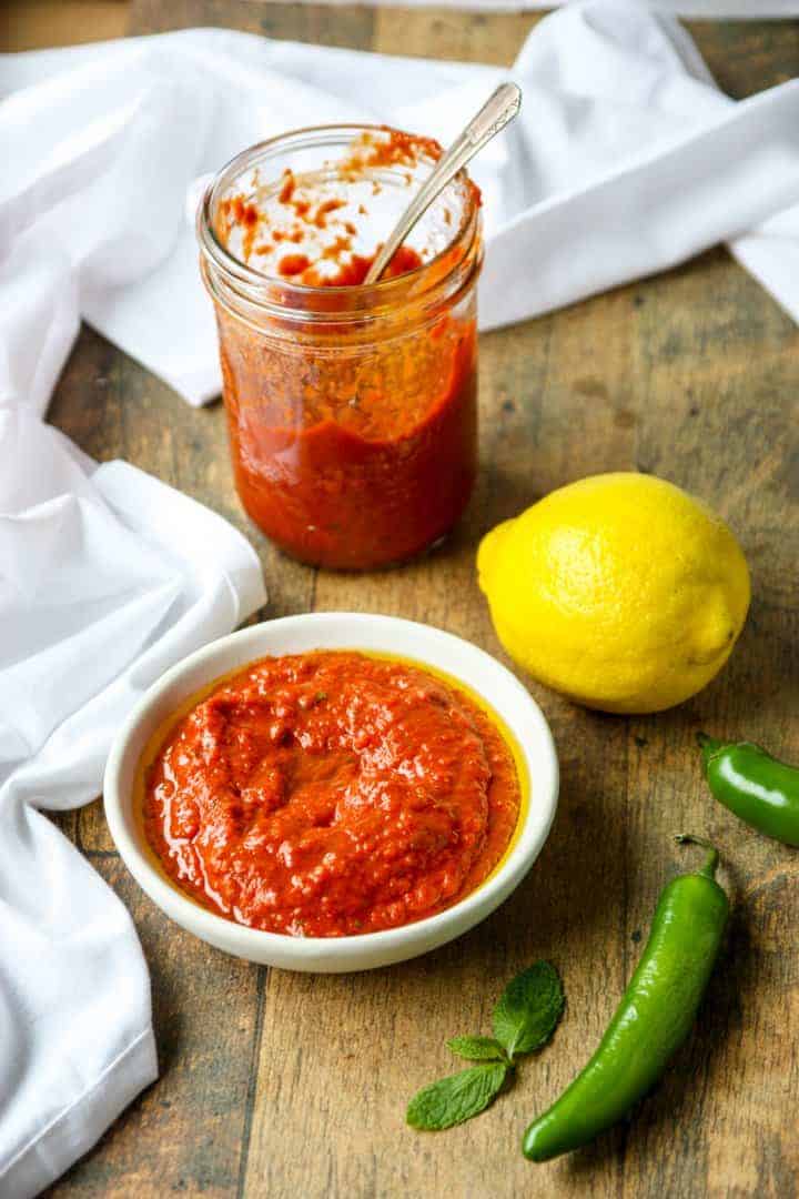 A bowl of hot sauce next to a half-empty jar of hot sauce