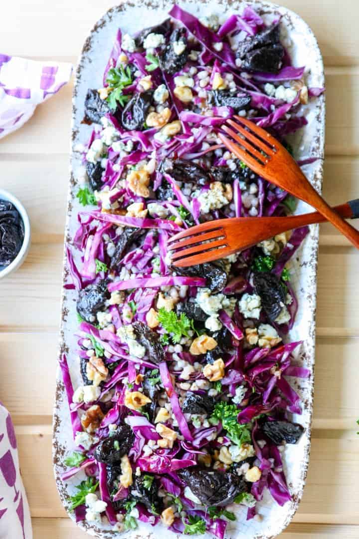 A wooden cutting board with a platter of salad
