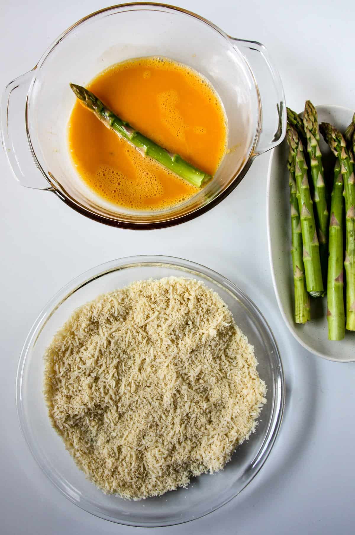 Asparagus being dipped in beaten egg.