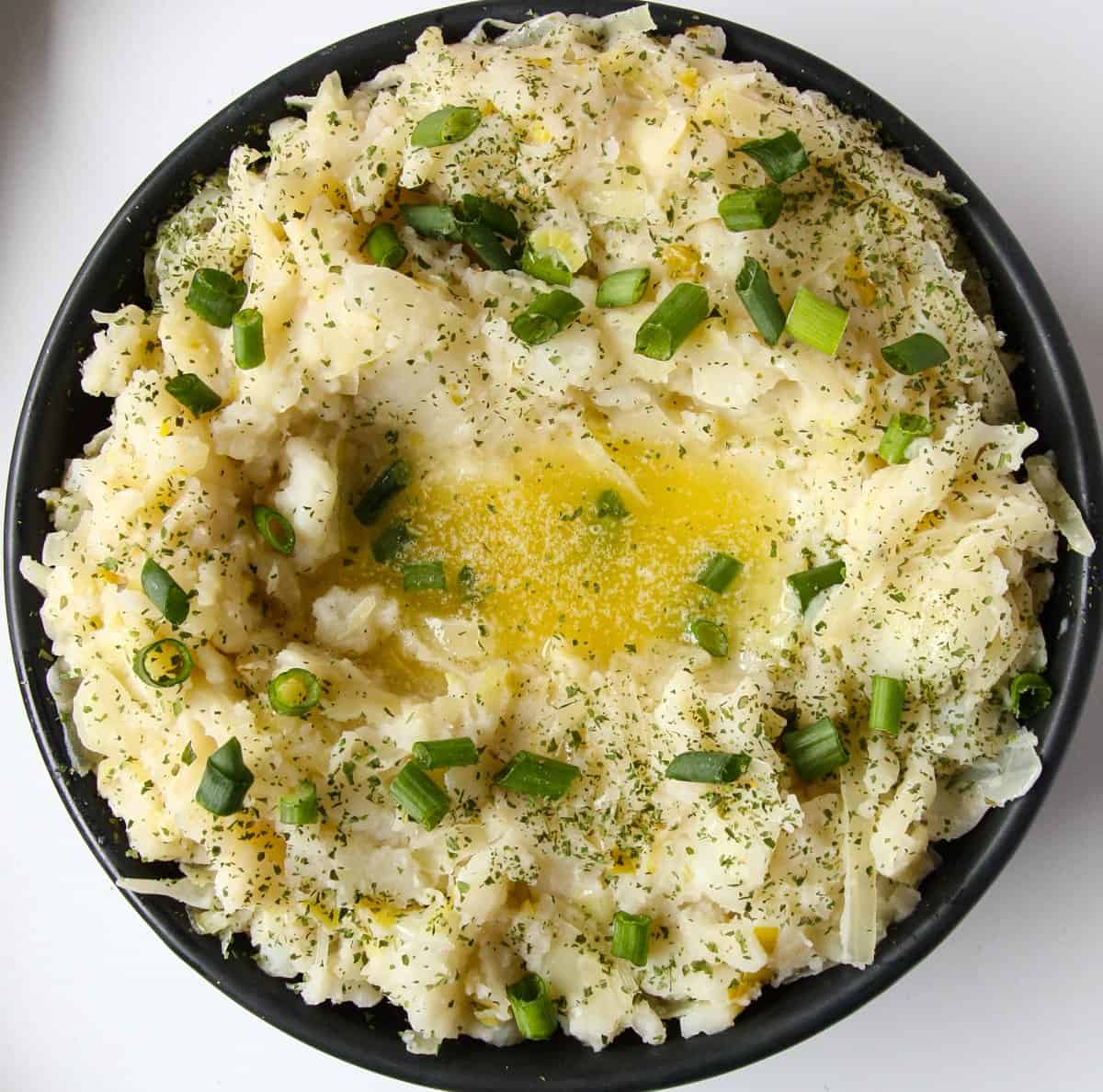 A dish of Irish mashed potatoes topped with butter and green onions.