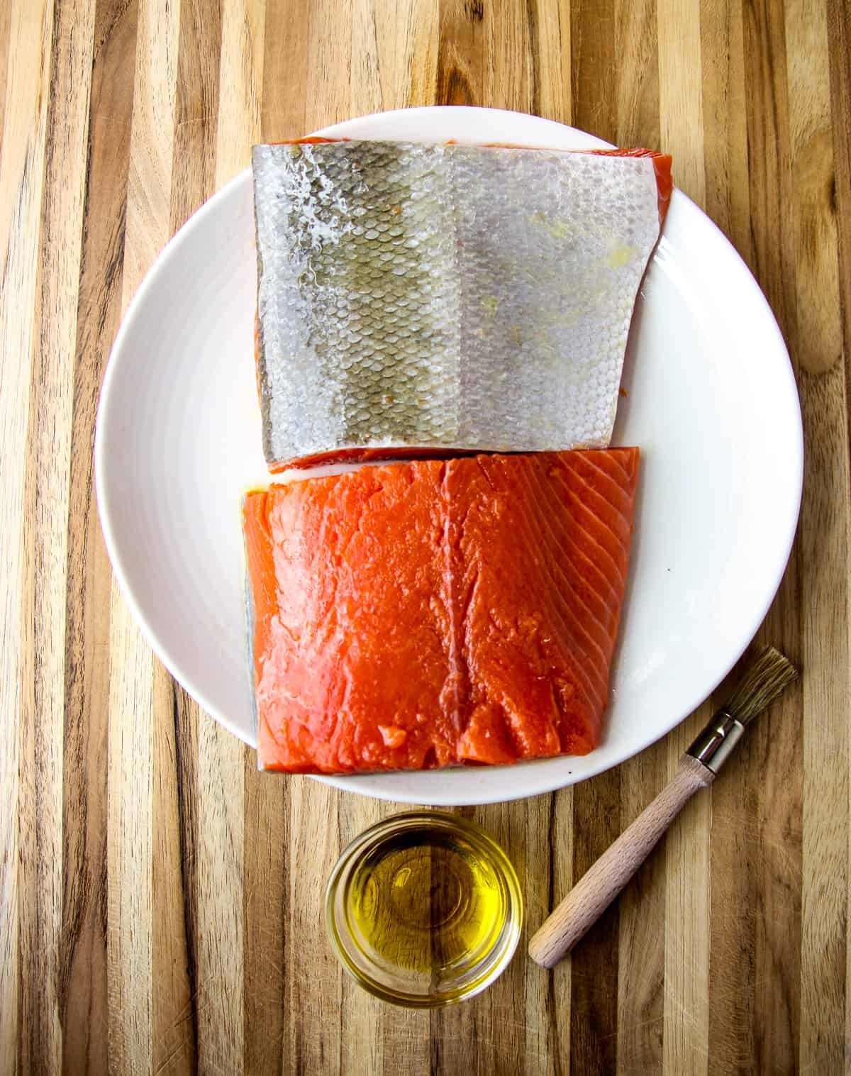 Salmon fillets being brushed with oil.