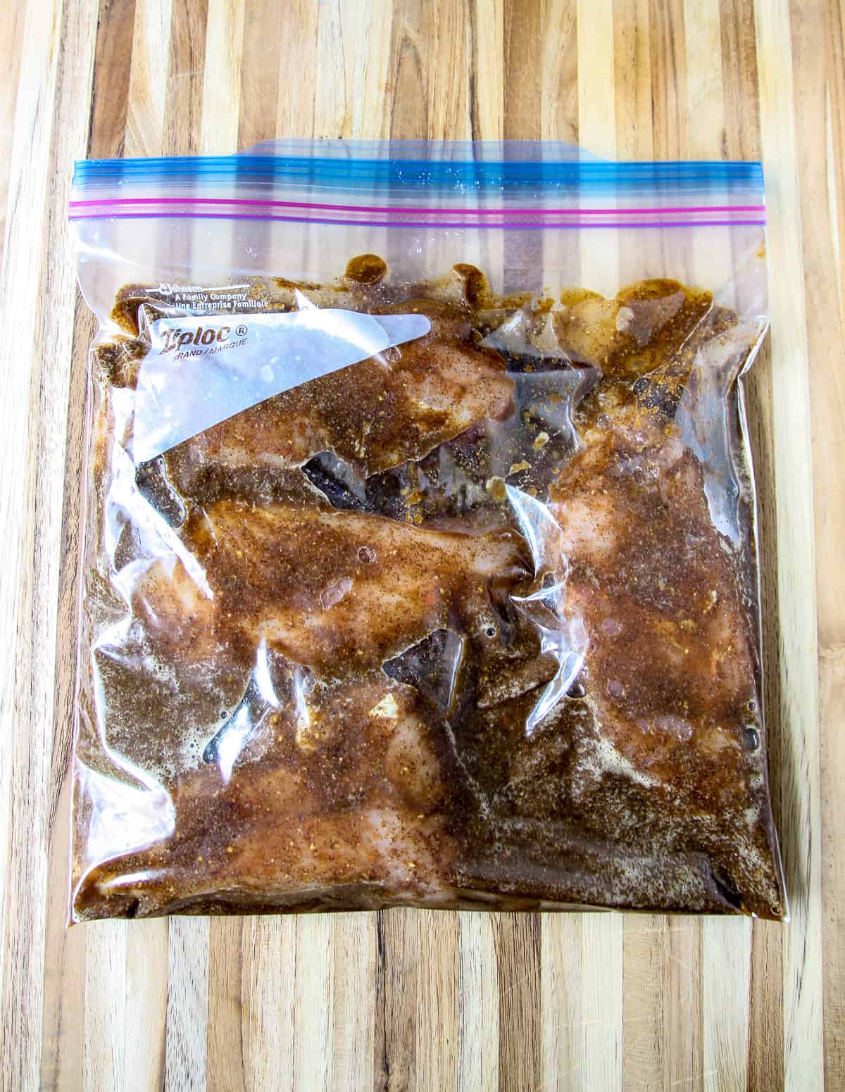Chicken marinating in a ziploc bag.