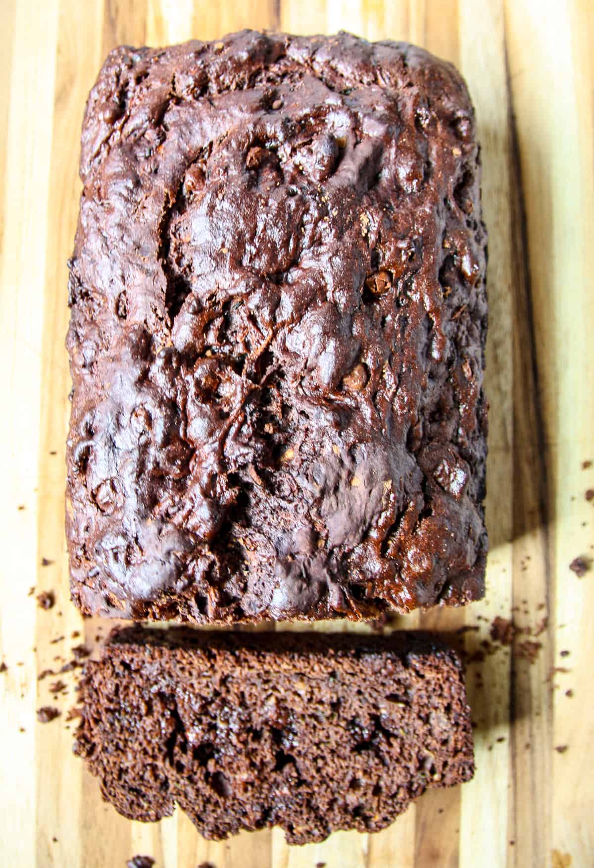 A loaf of gluten-free chocolate zucchini bread with a slice cut.