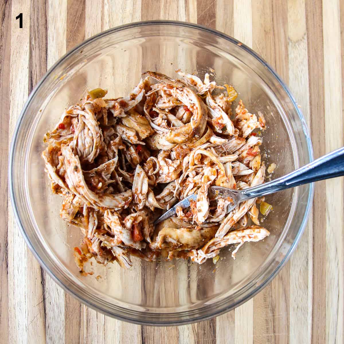 The turkey and salsa being combined in a glass bowl.