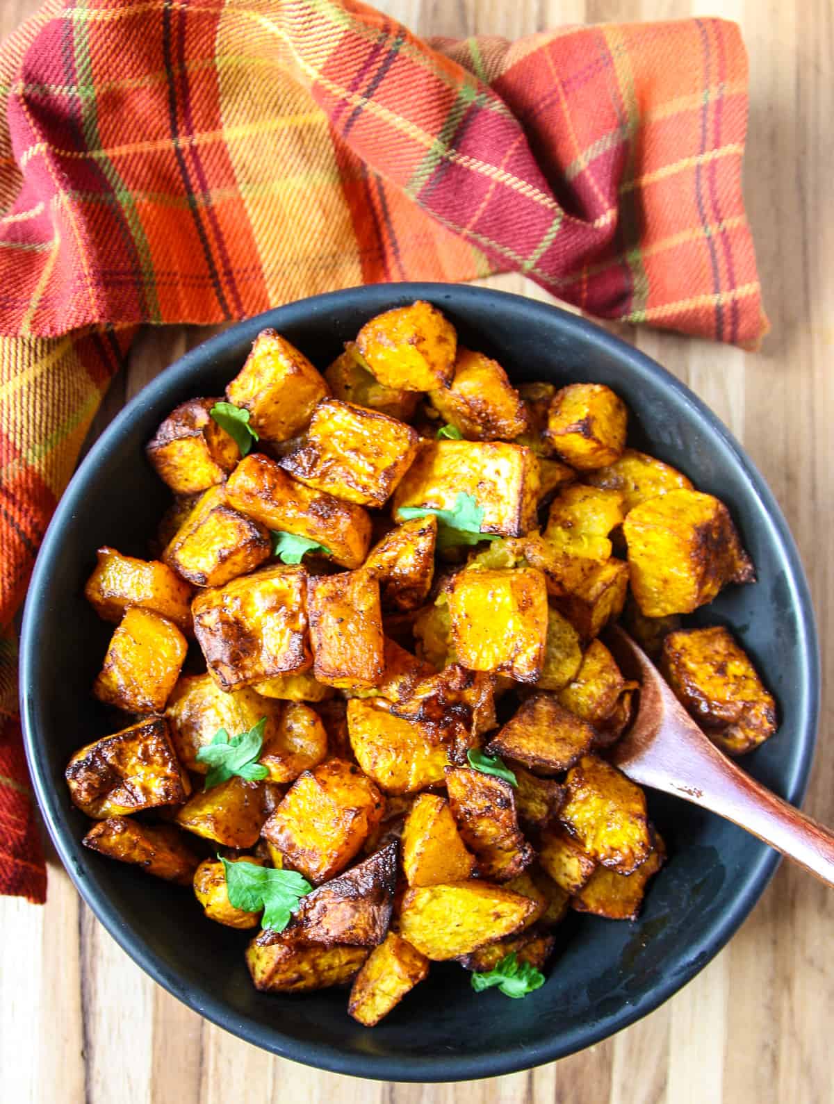 An overhead view of air fried butternut squash cubes in a black bowl.