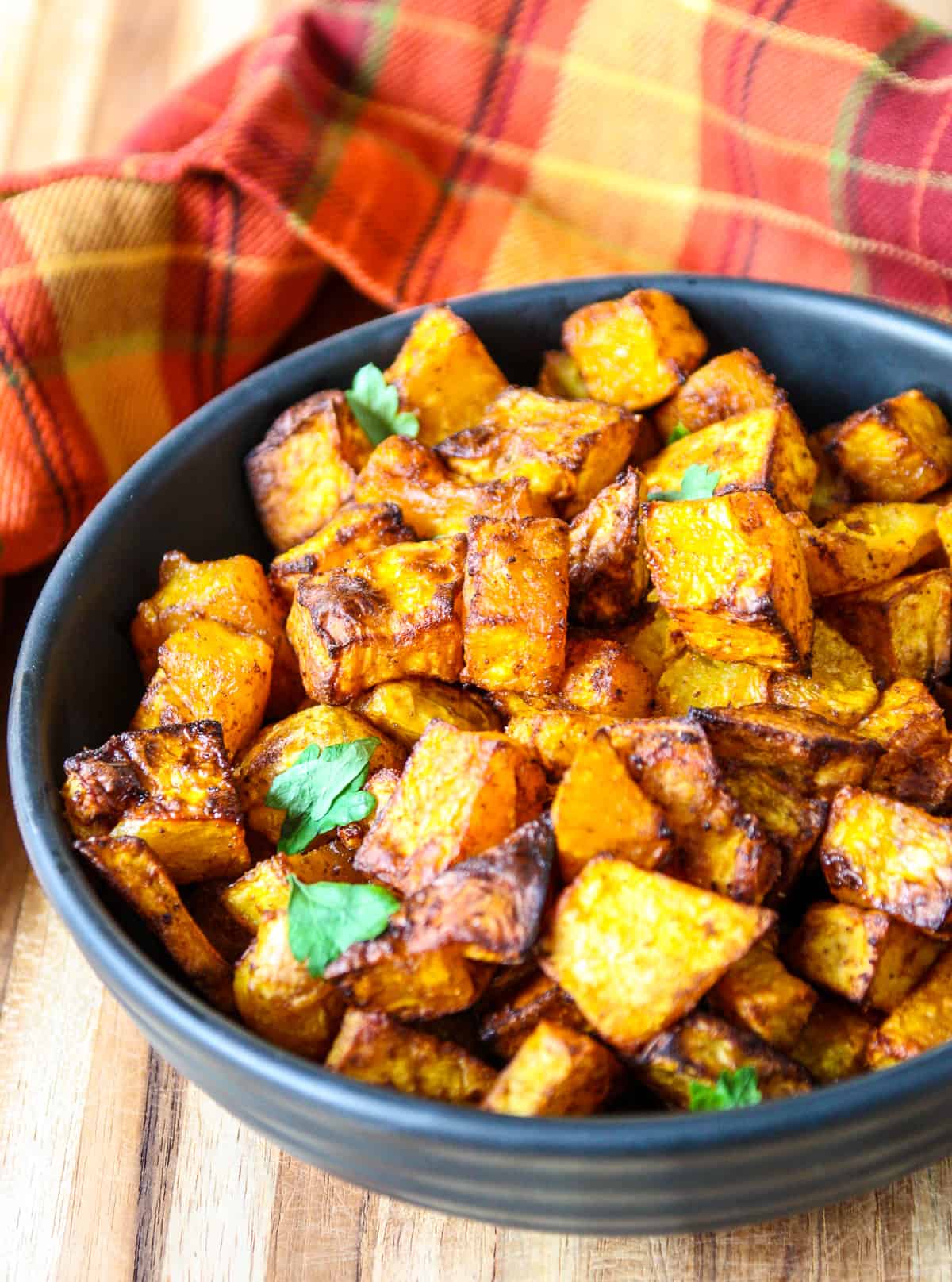 A black bowl filled with roasted squash cubes.