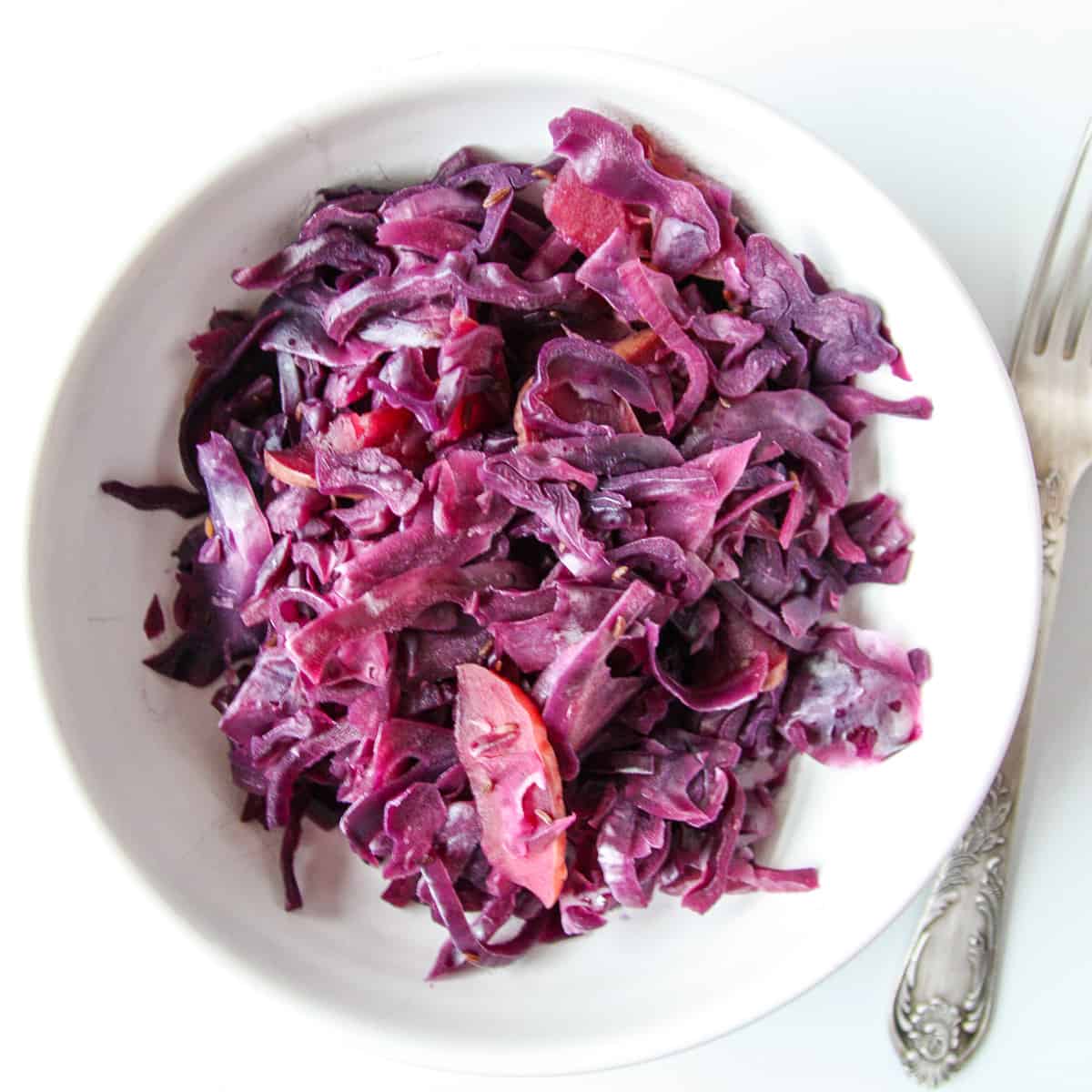 Braised red cabbage with apples in a white dish.