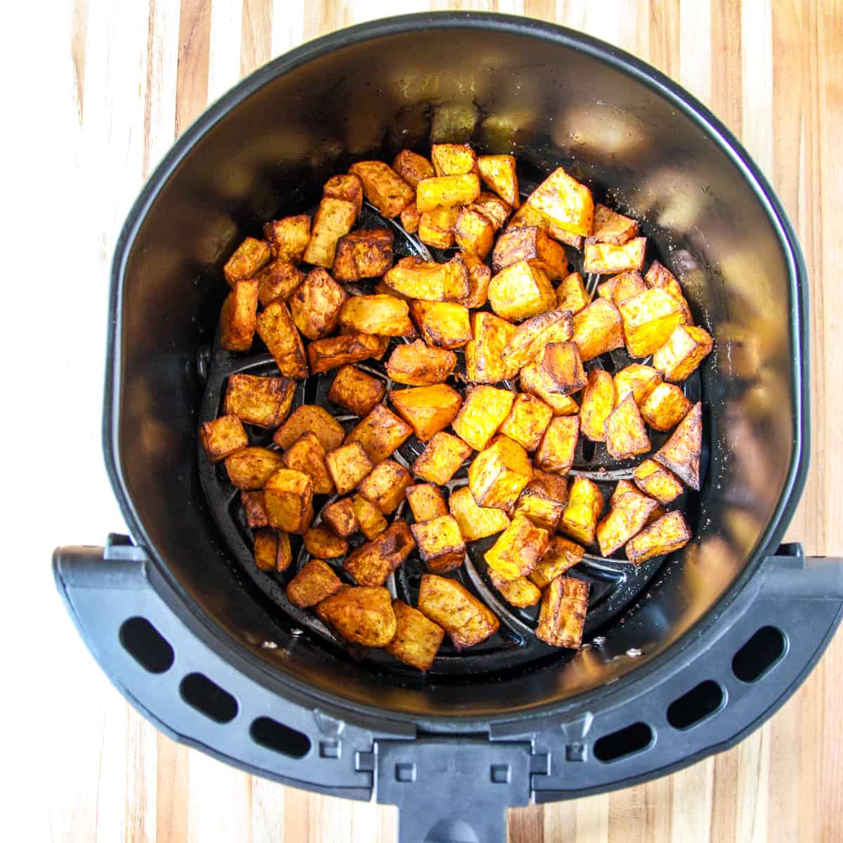 Roasted butternut squash cubes in an air fryer basket.