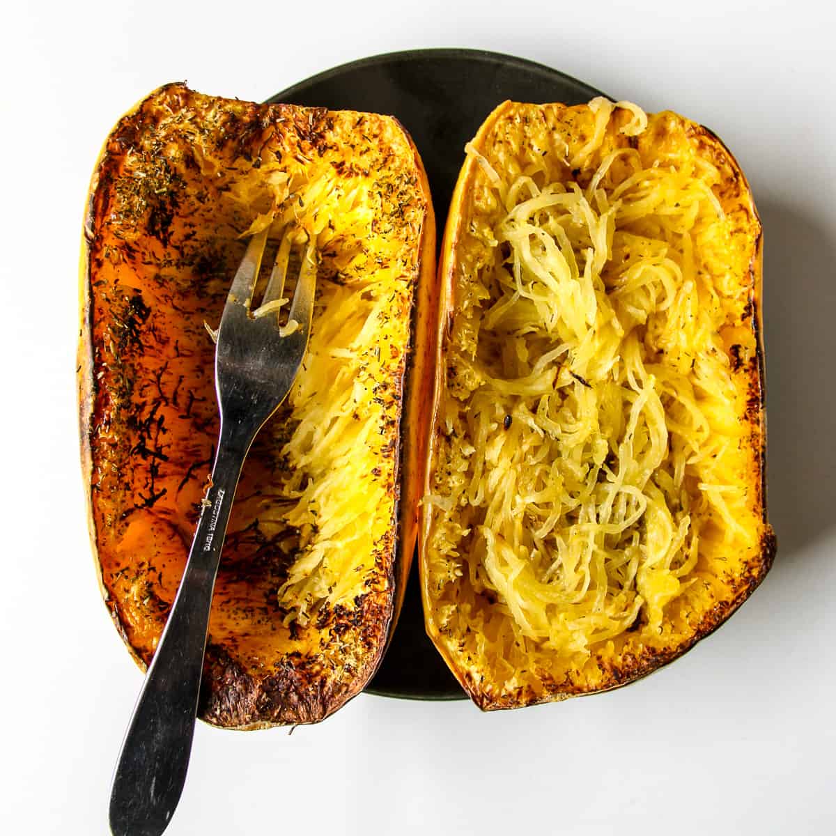 A fork being used to fluff the spaghetti squash into strands.