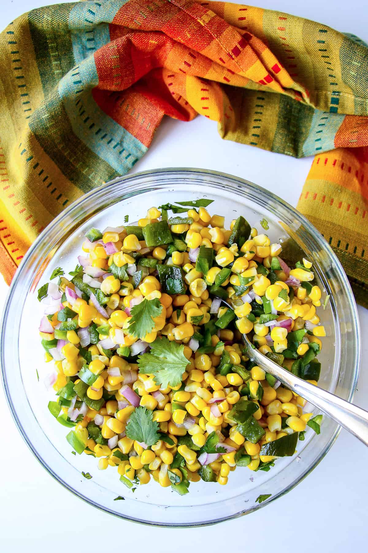 A bowl of chipotle corn salsa garnished with cilantro leaves.