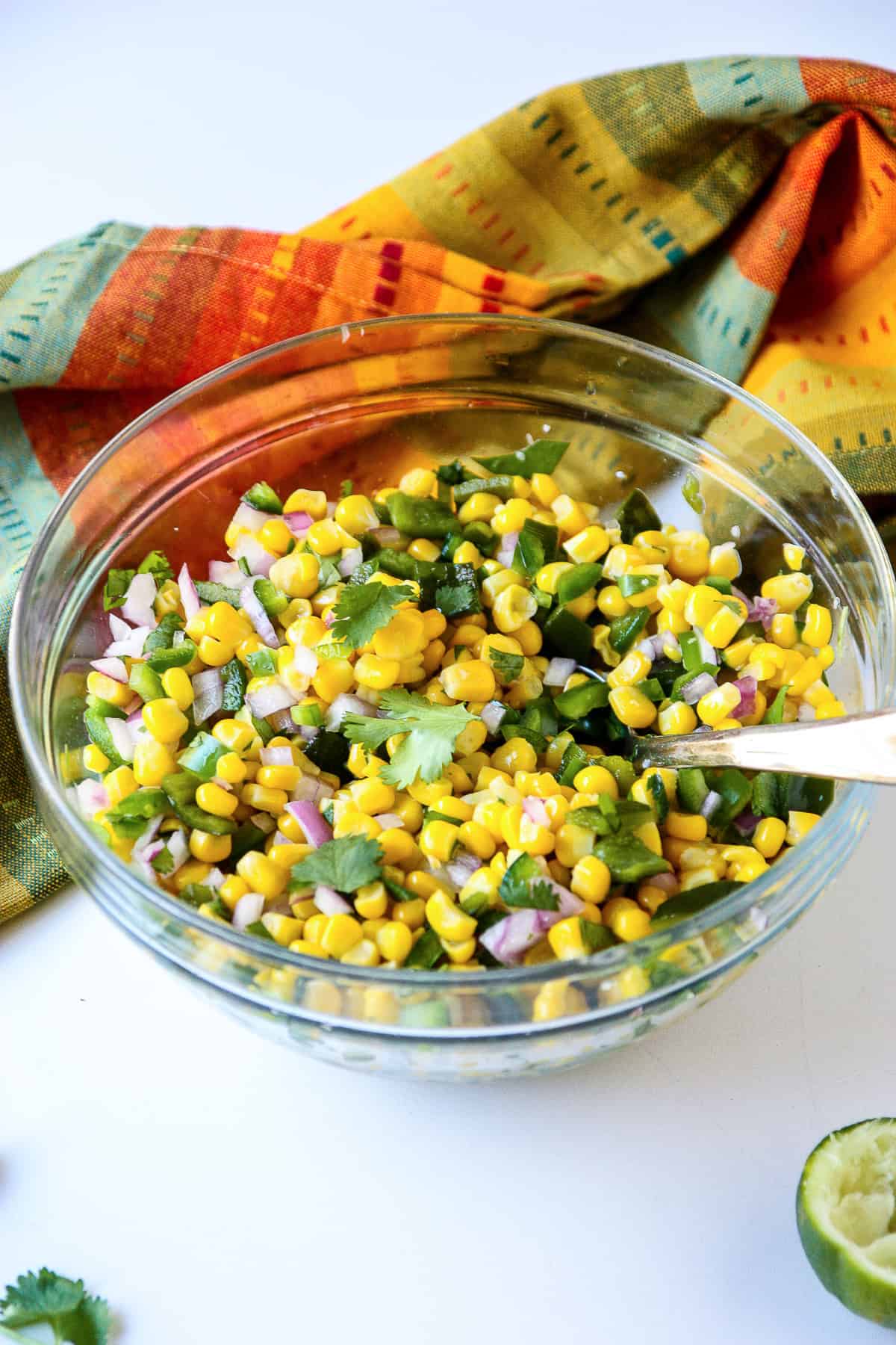 Salsa ingredients being tossed together in a glass bowl.