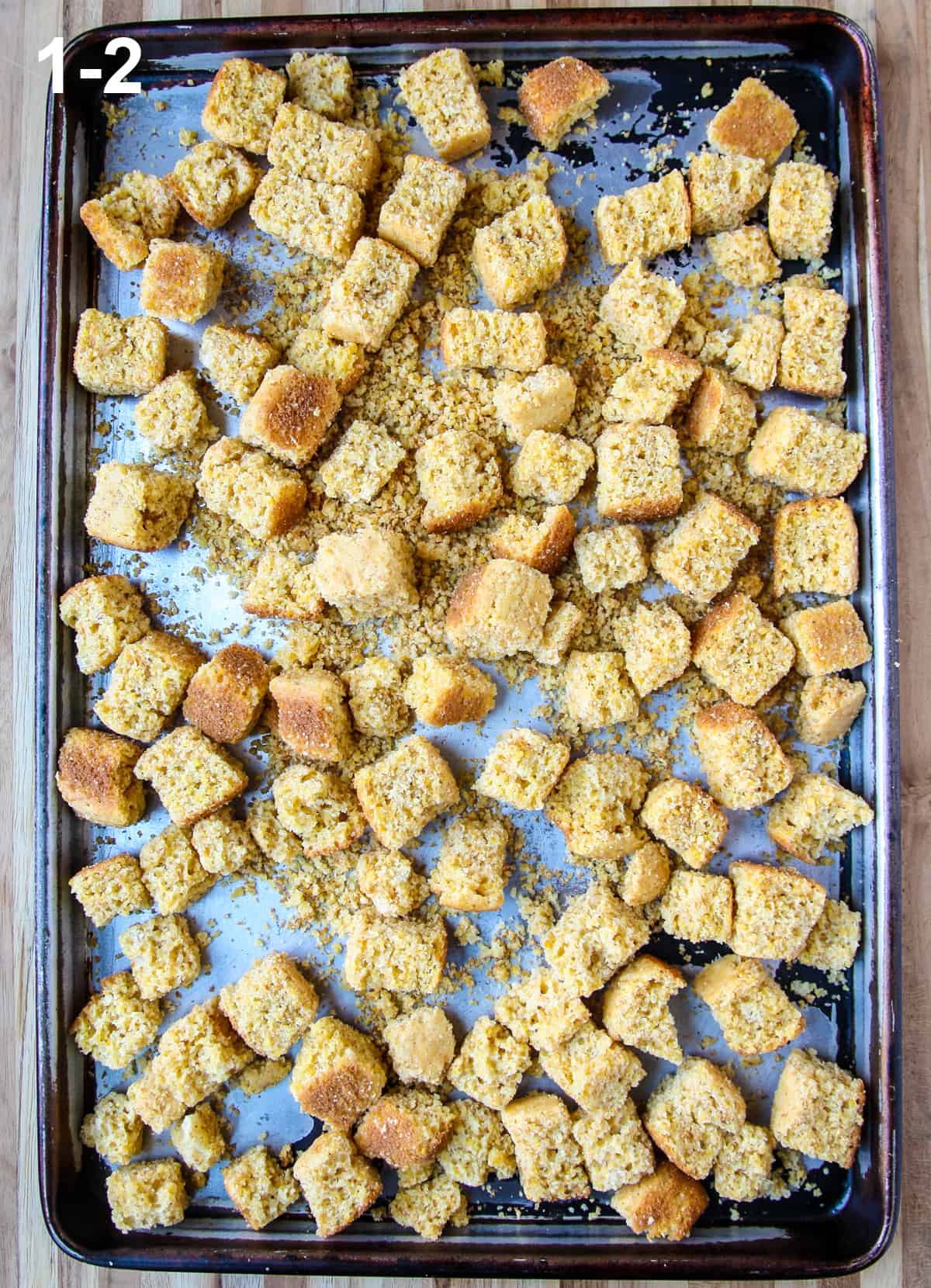 Cubes of cornbread on a baking sheet ready to toast in the oven.