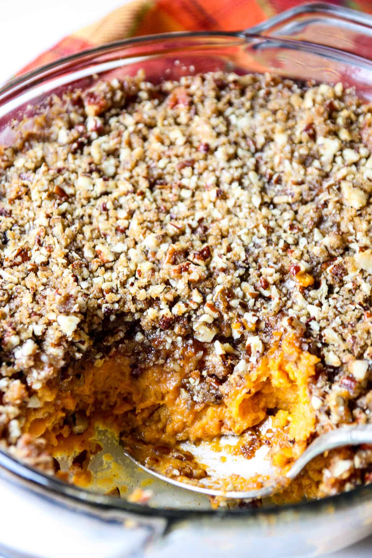 A close up of a serving spoon in a dish of sweet potato crunch casserole.
