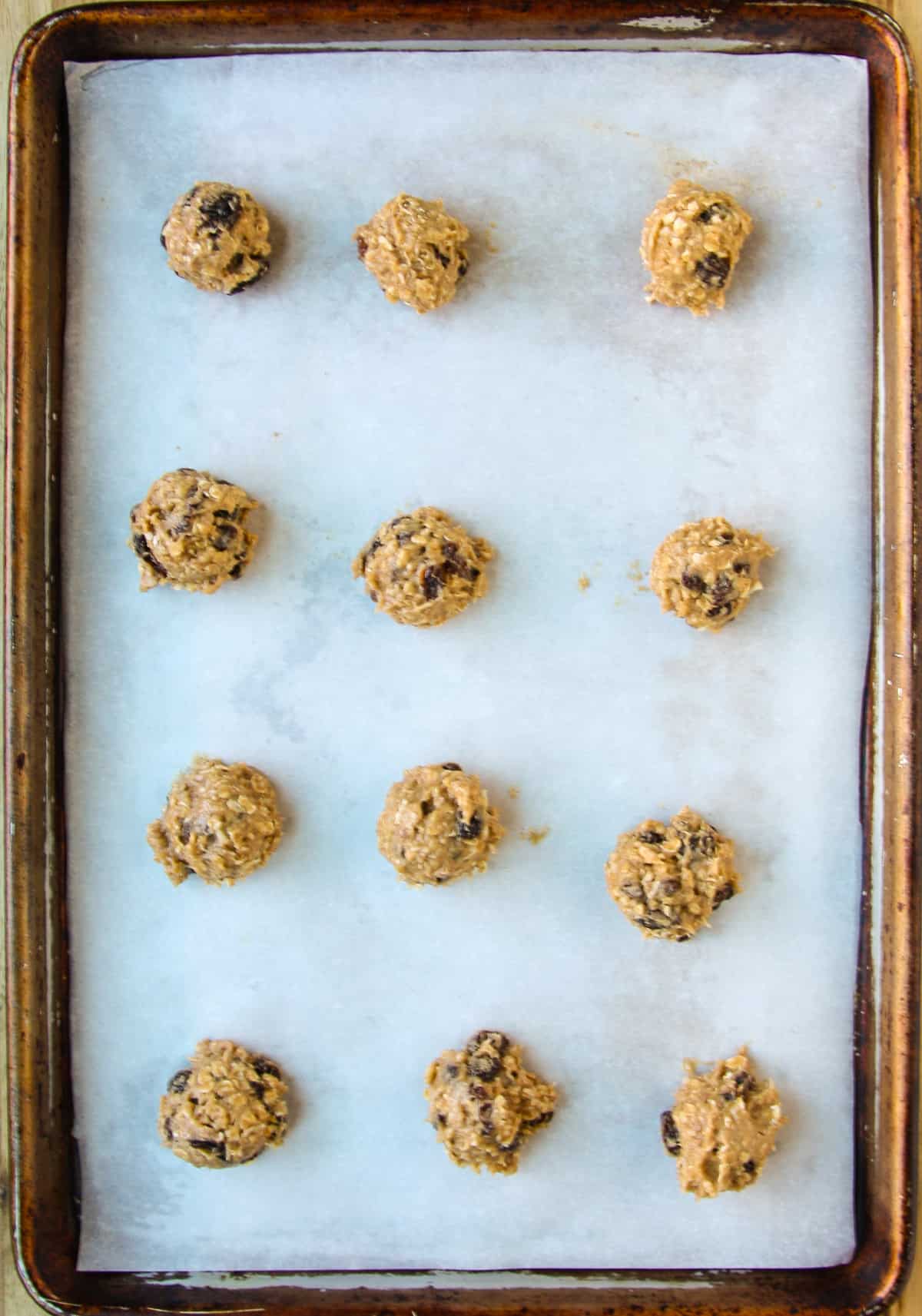 Balls of cookie dough on a parchment lined baking sheet.