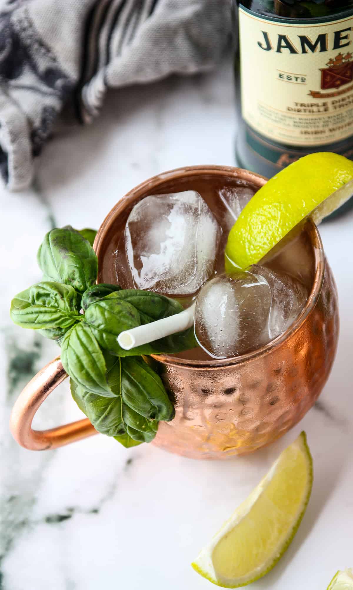 A close up of an Irish whiskey cocktail with a bottle of Jamesons whiskey in the background.