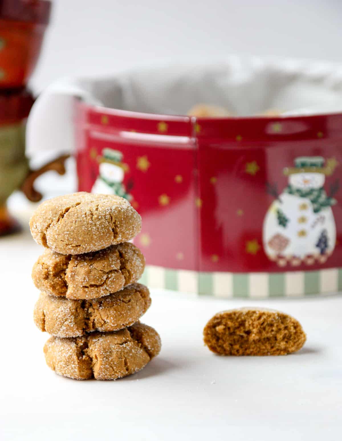A stack of four cookies next to a Chistmas cookie tin.