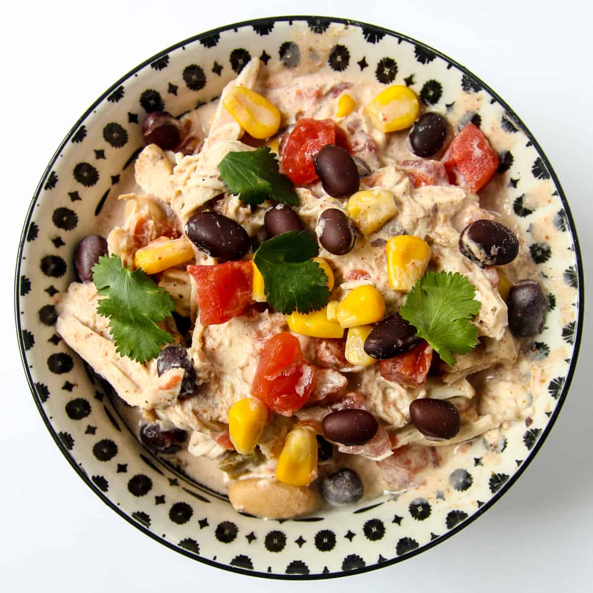 A black and white bowl filled with cream cheese chicken chili.