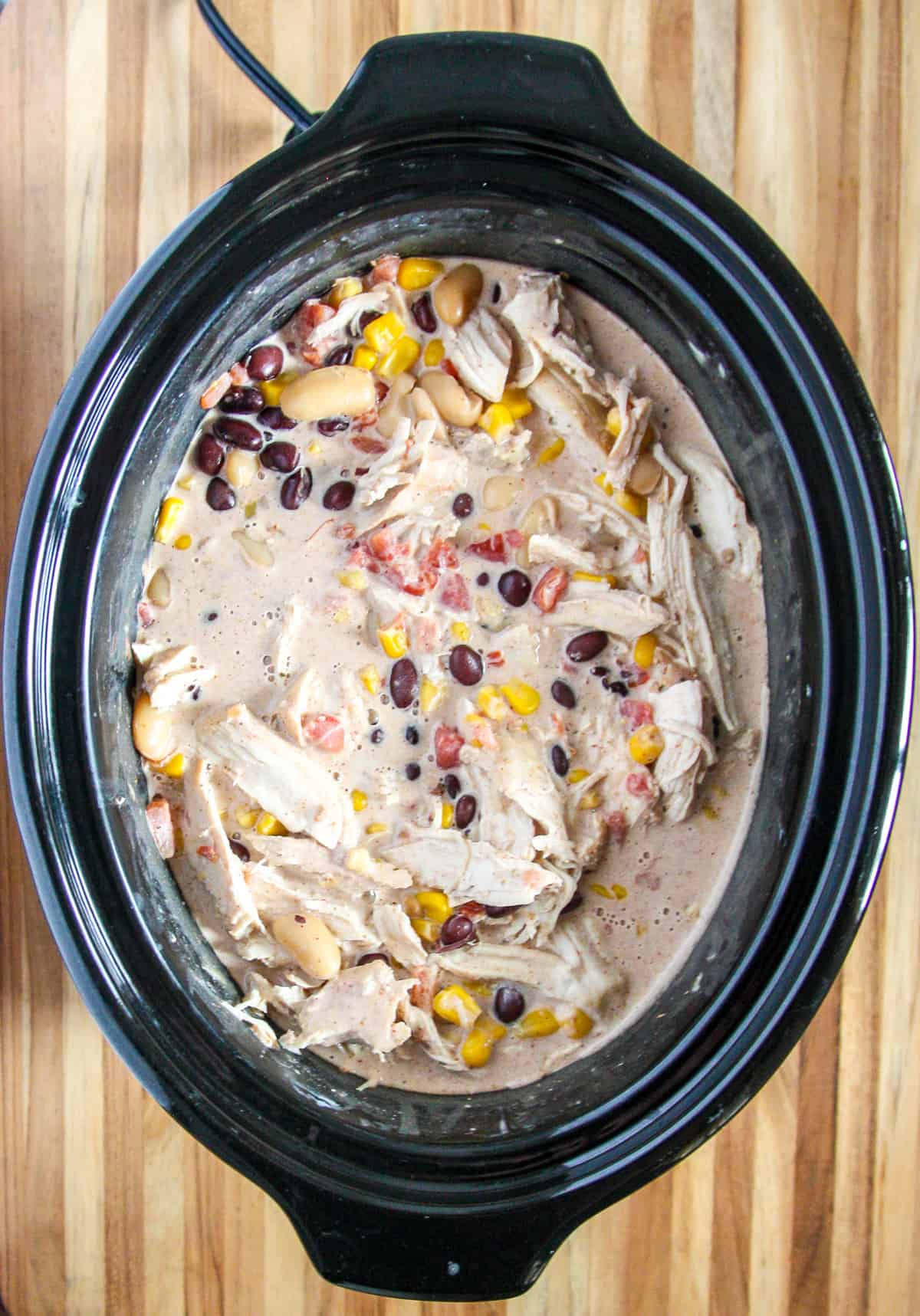 The cooked chicken added back to the slow cooker after being shredded.