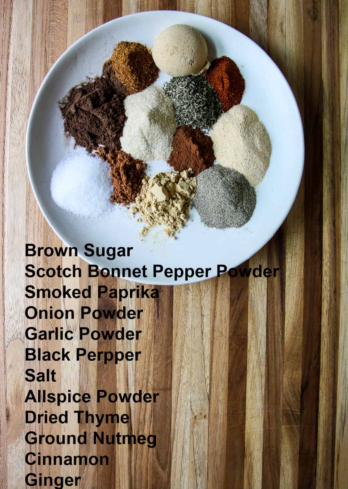 All of the individual ingredients for making Jamaican jerk seasoning blend on a white plate.