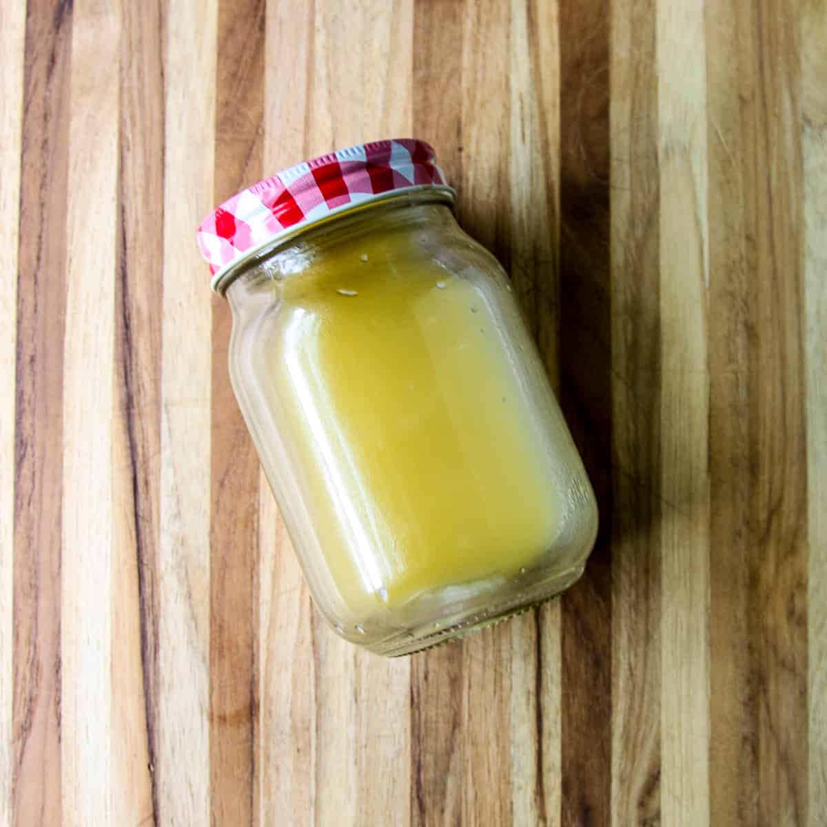 The combined salad dressing ingredients in a glass jar with a red and white lid.