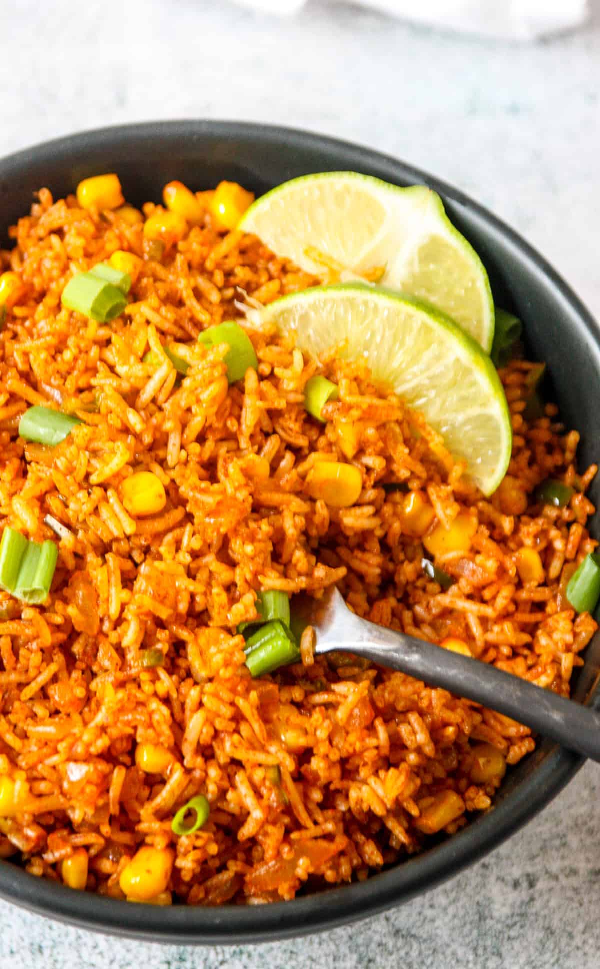 A fork dipping into a black bowl of Mexican fried rice.