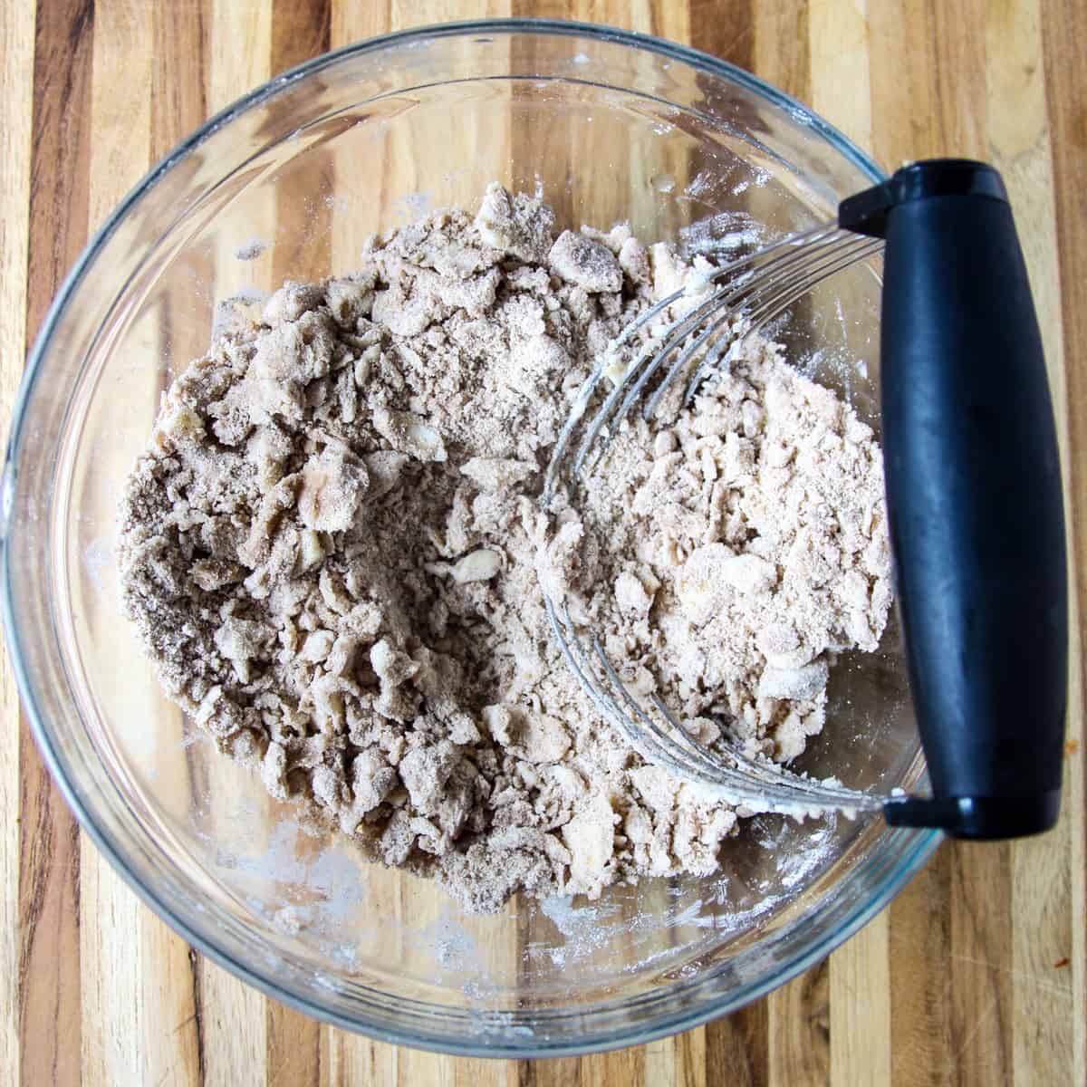 The butter being cut into the streusel ingredients with a pastry blender.