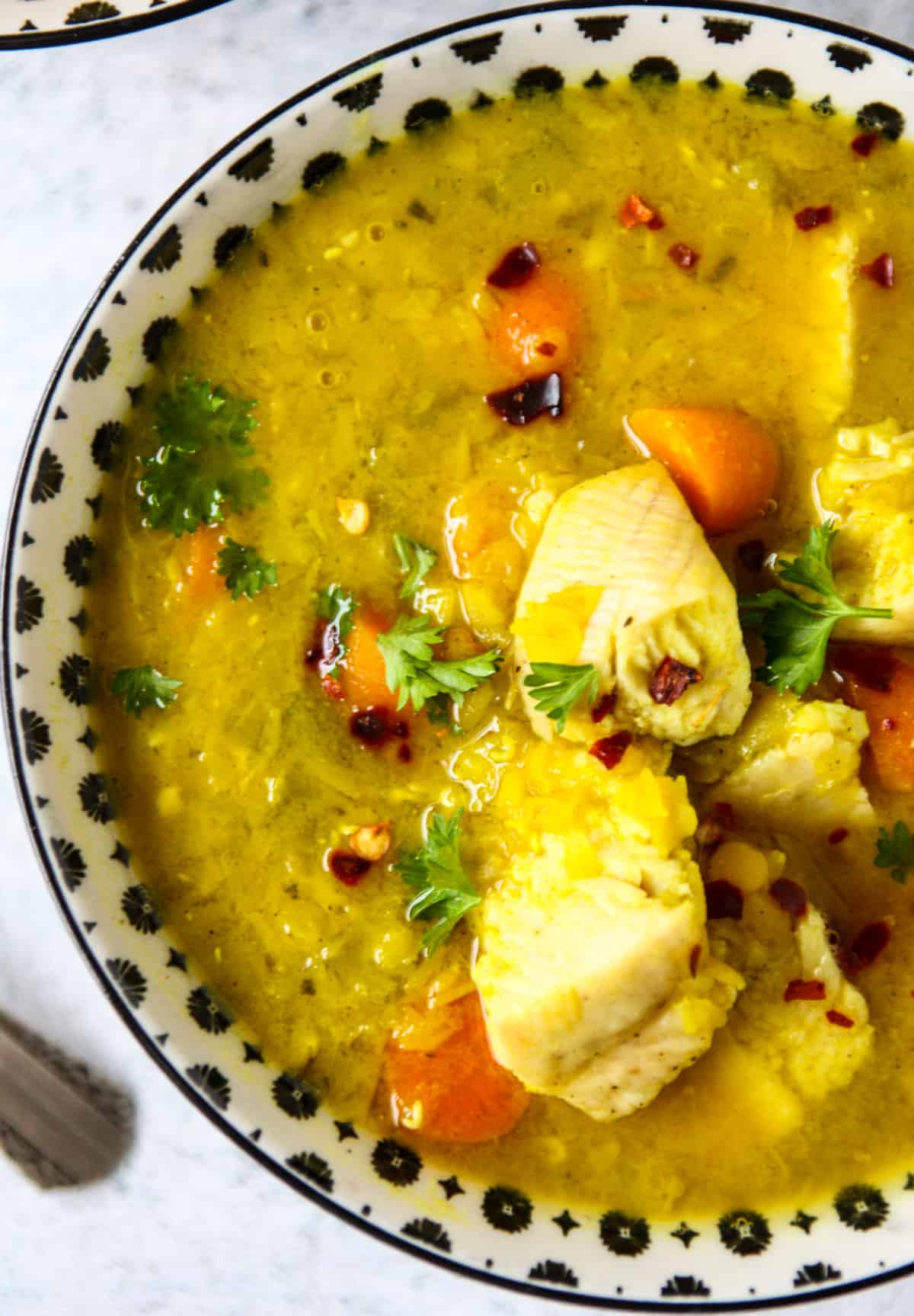 Turkey lentil soup in a black and white bowl.