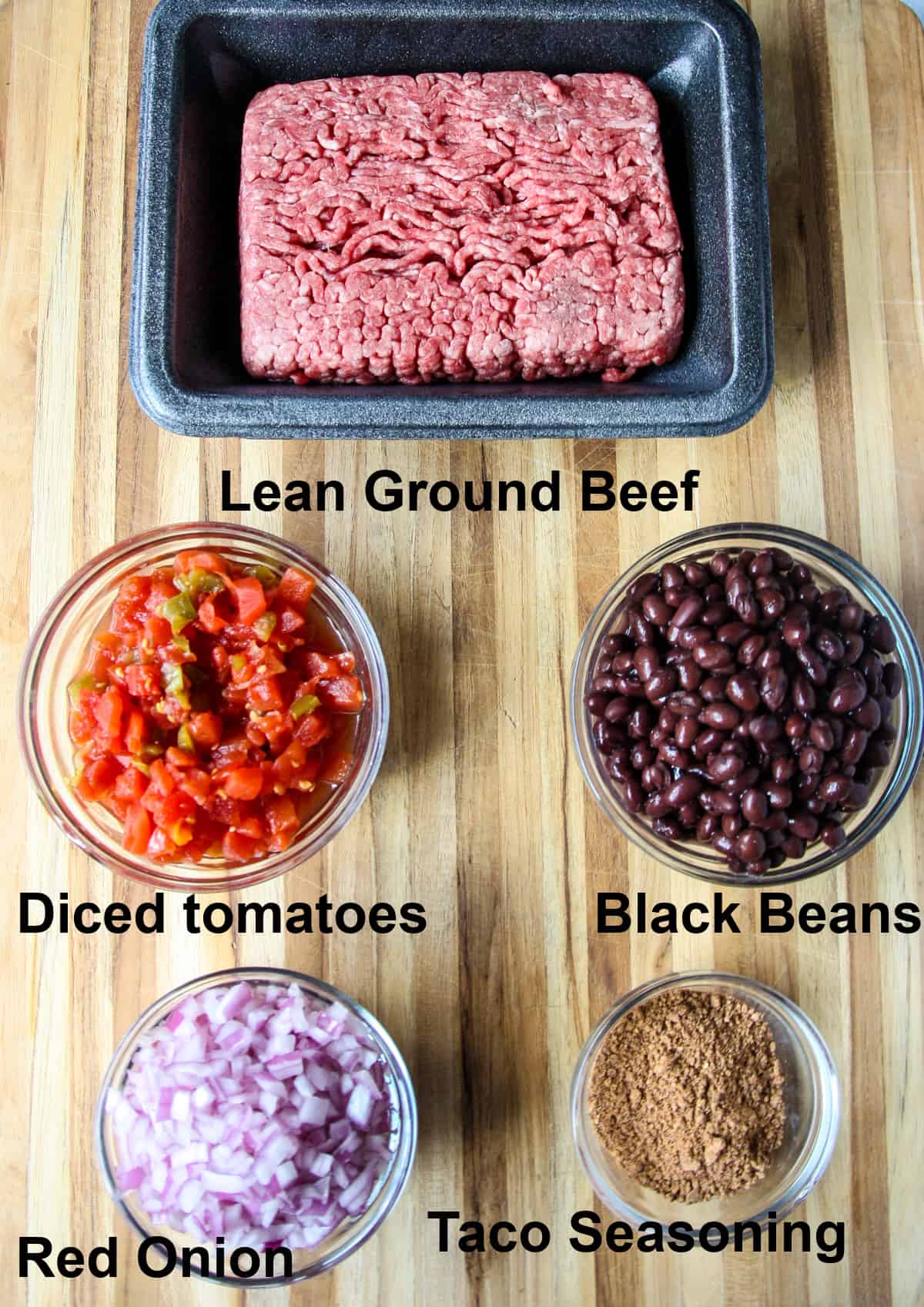 The ingredients for making the taco meat on a wood cutting board.
