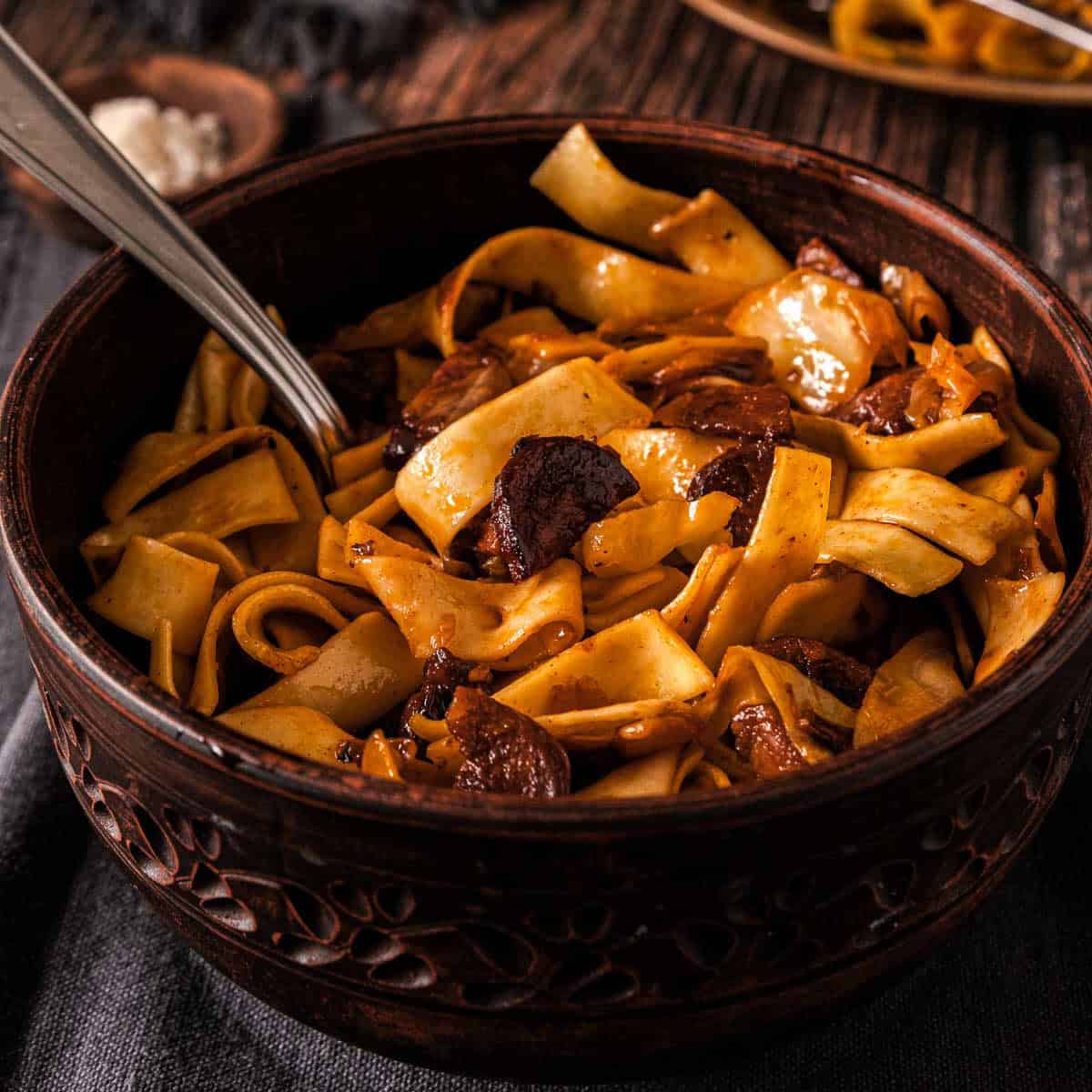 A wooden bowl filled with noodles and cabbage.