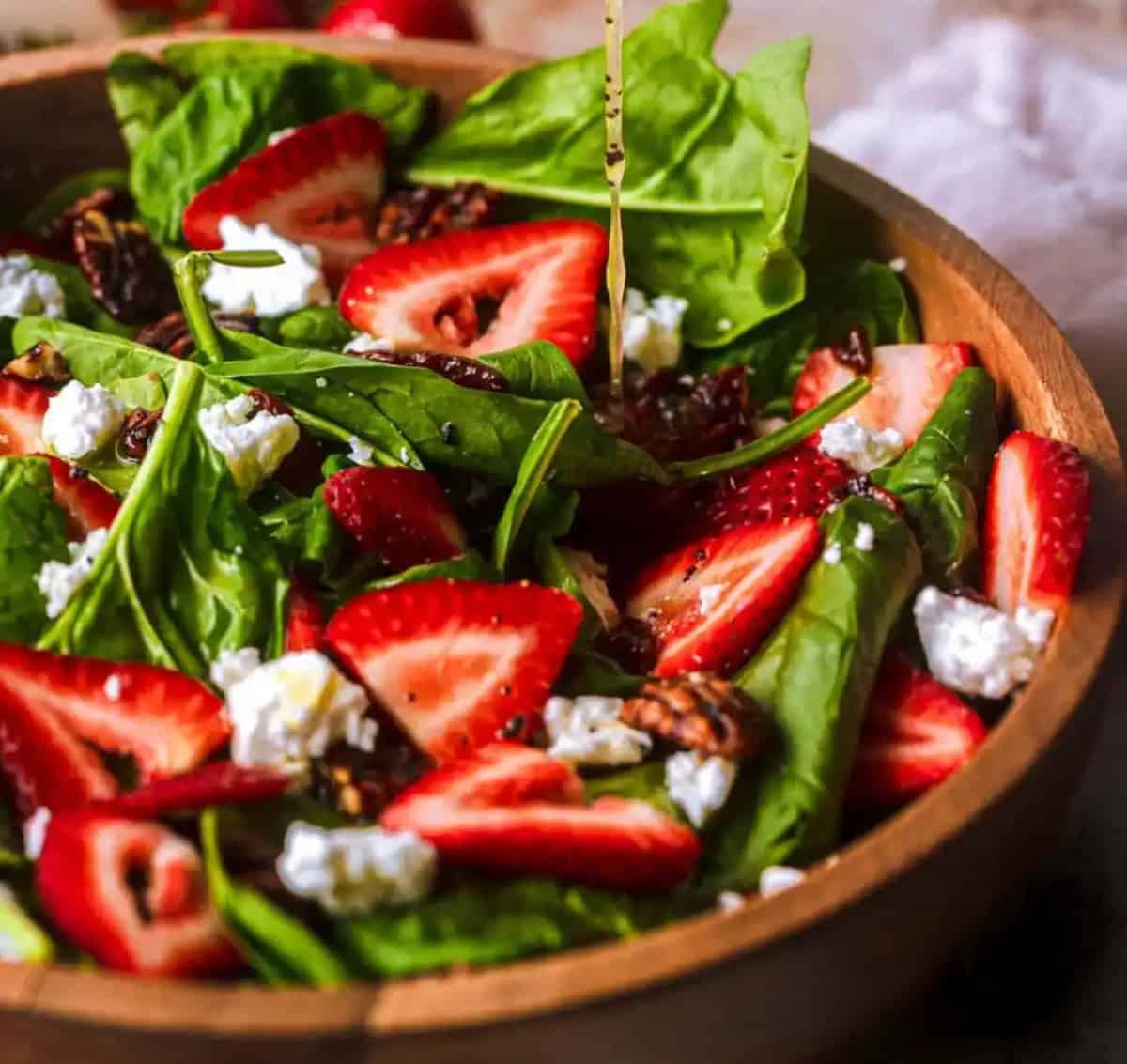 Strawberry spinach salad in a wood bowl.