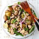 Tuna Potato Salad in a glass bowl with two wooden forks.