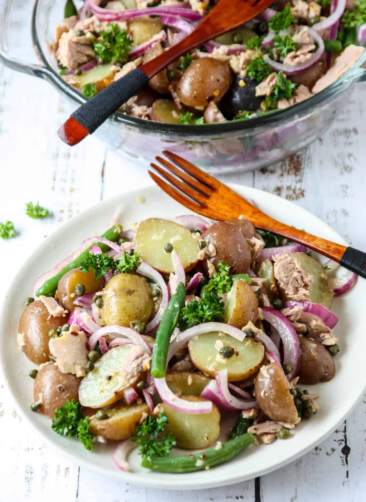 Tuna potato salad on a white plate with a wooden fork.